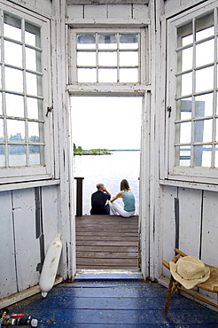 View through a cottage door with couple sitting on steps, Lake of the Woods, Kenora, Ontario