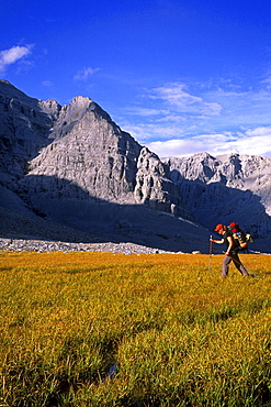 Hiker on grass beneath walls of Mount MacDonald, Mayo, Yukon