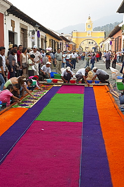 People working on a carpet made of sand & sawdust along the Good Friday processional route. Carpet-making is thought of as a sacrificial act, as the elaborate detail and time that go into the carpet making is a way for people to give something of themselves in memory of the crucifixion of Jesus. These carpets last on average 2 hours before they are destroyed by the many feet that march over them during a procession in Antigua Guatemala., Sacatepuquez, Guatemala