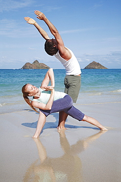 Hawaii, Oahu, Lanikai, Young couple do yoga on beach.