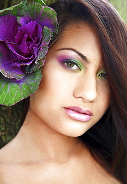 Hawaii, Oahu, Fashion model poses with plant behind ear.