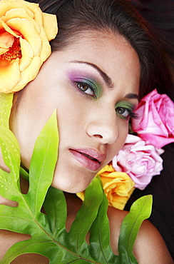 Hawaii, Oahu, Fashion model poses among flowers and leaf.