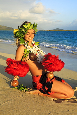 Hawaii, Oahu, Lanikai Beach, Young woman dancing hula along sandy shore with Uli'uli.