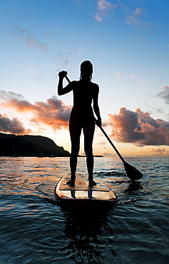 Hawaii, Kauai, Woman stand up paddling in ocean, Beautiful sunset.