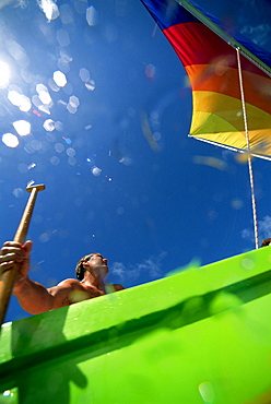 Hawaii, Oahu, Lanikai, Man in colorful sailing canoe.