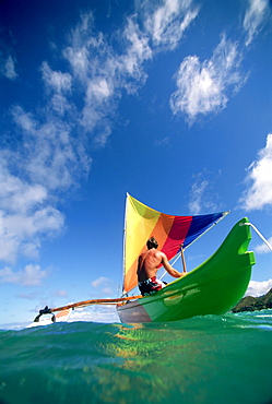 Hawaii, Oahu, Lanikai, Man in colorful sailing canoe.