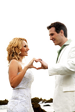 Oahu, Hawaii, Wedding couple smiling at each other, hands in the shape of a heart.