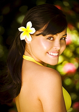 Hawaii, Oahu, Beautiful headshot of a young girl with a plumeria in her ear.