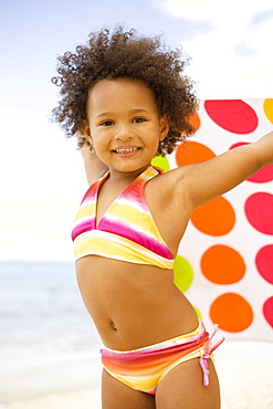 Hawaii, Oahu, Adorable little girl holding a polka-dot towel along the waters edge.