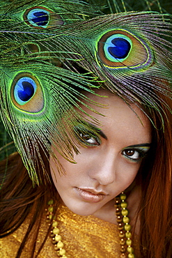 Hawaii, Oahu, Headshot portrait of Beautiful Gorgeous Young Girl with Peacock Feathers near her face wearing matching makeup, fabric and necklace.