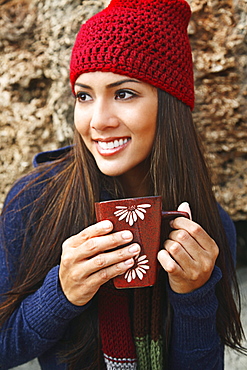 Hawaii, Oahu, Young woman outside in cozy winter weather drinking coffee.