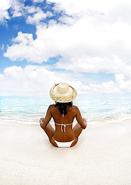 Hawaii, Woman sitting on beach in remote tropical location.