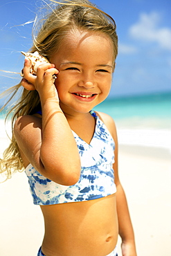 Hawaii, Oahu, Adorable little girl holding seashell along the waters edge.