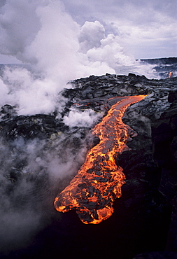 Hawaii, Big Island, Hawaii Volcanoes National Park, Molten lava flow, Steam clouds in distance.