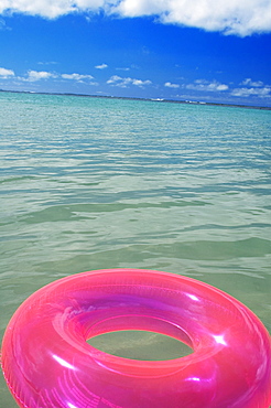 Pink swim ring floating in the ocean water.