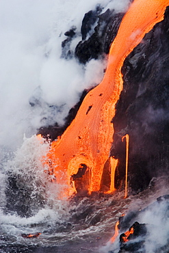 Hawaii, Big Island, near Kalapana, Pahoehoe lava flowing from Kilauea into frothy Pacific Ocean.