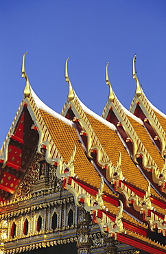 Bangkok, Thailand, Wat Benjamabophit (Marble Temple) top of gold trimmed temple, blue sky.