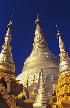 Burma (Myanmar), Yangon, Shwedagon Paya, close-up of three golden steeples in sunlight.