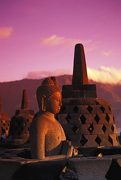 Indonesia, Java, Borobudor Temple and Buddha statue at sunrise, pink misty sky