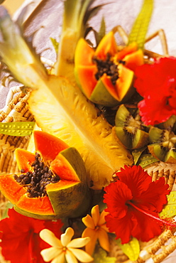 Colorful centerpiece with pineapple, papaya, kiwi, and hibiscus in woven basket