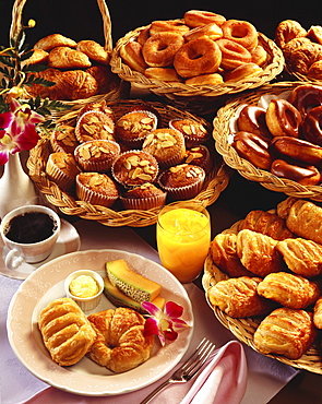 A breakfast selection of pastries with orange juice and coffee displayed on an elegant table.