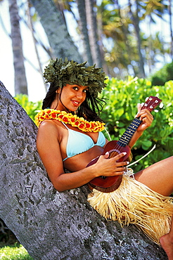 Hawaii, Hula girl with haku and ukulele leaning against tree