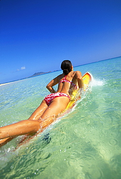 Hawaii, Oahu, Back view of woman on surfboard paddling out at Lanikai beach