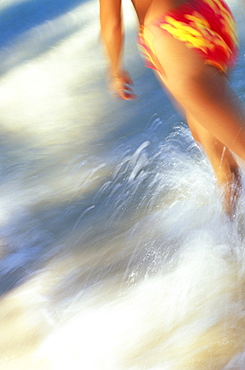 Hawaii, Oahu, Lanikai, Woman blurred close-up of woman walking on beach, water splashing