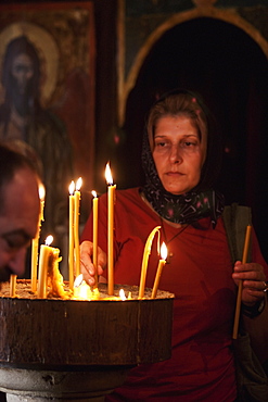 Woman Lighting Candles In The Church Of St. Nicholas, Kotor, Montenegro