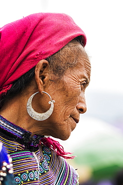 Portrait of a senior woman wearing a headscarf and earrings with colourful dress, Bac Ha, Lao Cai, Vietnam