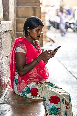 A young Indian woman sits using her cell phone, Jaisalmer, Rajasthan, India