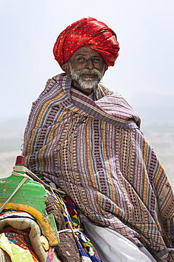 Man of the Dhebariya Rabari community in traditional cloth with a dromedary, Great Rann of Kutch Desert, Gujarat, India, Asia