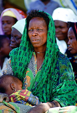 Woman with tribal markings on her face holding her baby close, Northern Nigeria