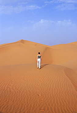 Tourist climbing up a sand dune in the Sahara Desert, Morocco