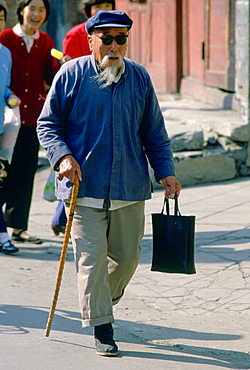 Old man walking with a stick in Beijing in China