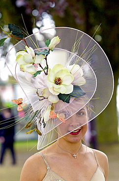 Race-goer wearing an elaborate hat with flowers and silk butterflies at Royal Ascot Races