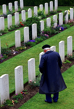 Veteran in military cap  looking at war graves in Commonwealth war cemetery, Normandy, France.