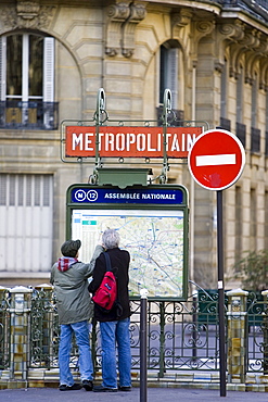 Tourists on foot study Metropolitain subway map for the Paris Metro in Rue du Bac, Left Bank, Paris, France