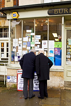 Couple browse the window of a newsagent's shop at Burford in the Cotswolds, United Kingdom