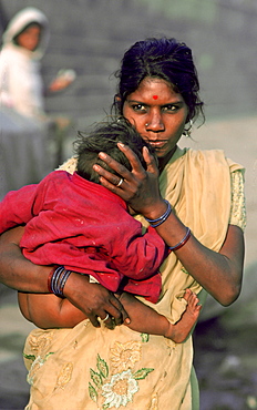 Mother holding her young baby as she walks through the streets of Delhi, India