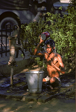 Boy having an early morning wash from a water pump in Delhi, India.