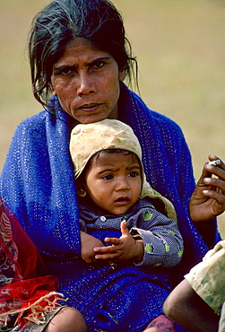 A mother sits smoking with her child on her  lap, Nepal