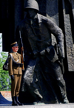 Soldier stands at attention with a rifle to guard the Warsaw Uprising Monument, Poland.