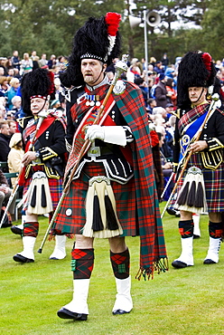 Drum Major leads massed band of Scottish pipers at Braemar Games Highland Gathering, Scotland