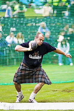 Man competes in shot put contest at the Braemar Games Highland Gathering, Scotland, UK