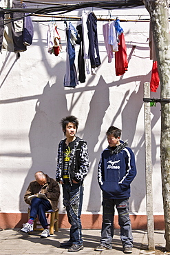 Teenagers stand by a man sleeping in Zi Zhong Road, old French Concession Quarter in Shanghai, China