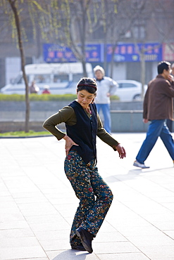 Woman practises Tai chi as part of her morning exercise in the park by the City Wall of Xian, China