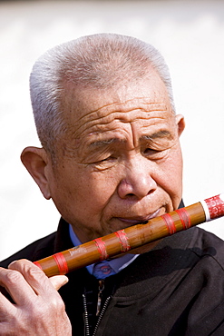 Man plays a Dizi flute in the park by the City Wall, Xian, China