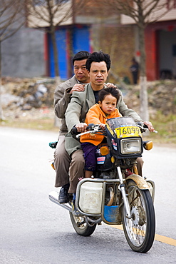 Men and child on a motorbike in Guilin, China. China has a one child family planning policy to reduce population.