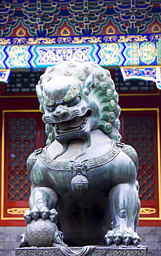 Statue of a bronze male lion with paw on a ball at The Summer Palace, Beijing, China